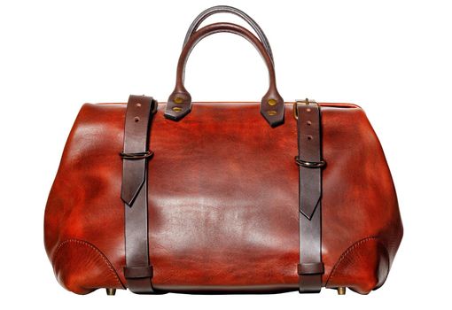 Leather red and brown travel bag with pulling straps on the sides and brass buckles in vintage style on a white background.