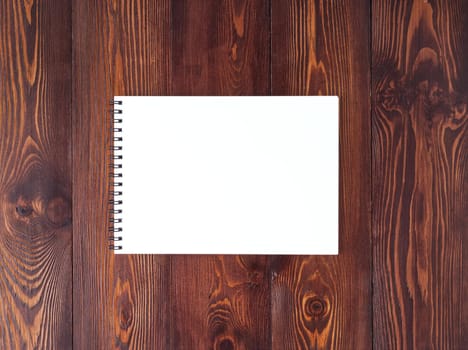 The open notepad with spiral on dark brown wooden table, top view
