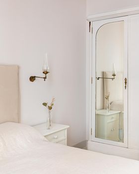 A part of bedroom interior with cozy bed and vintage wardrobe with mirror. Retro and classic style