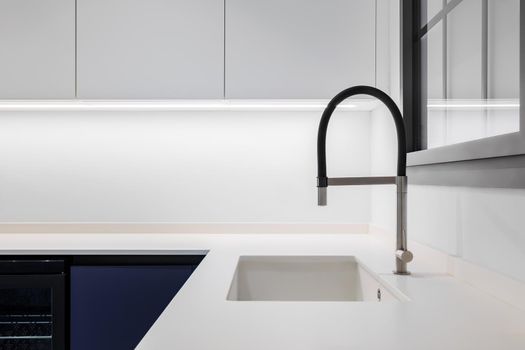 Black faucet with a white sink in a stylish modern kitchen. Minimalism in refurbished apartment
