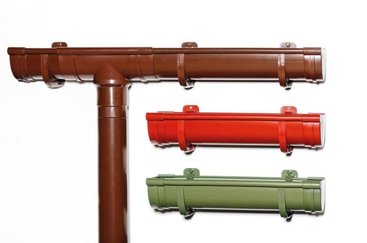 Plastic gutters for draining water from the roof of the house, brown, red, green. Downpipes, close-up, copy space.