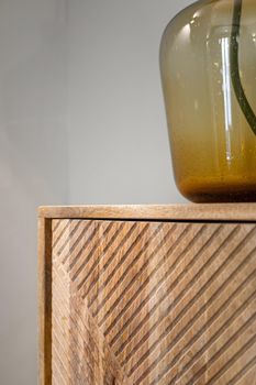 Detail of the cupboard with transparent vase. Wooden furniture in interior