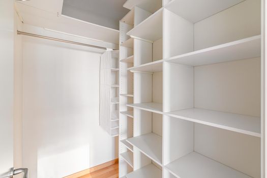 Interior of small, white and empty dressing room with shelves and no clothes