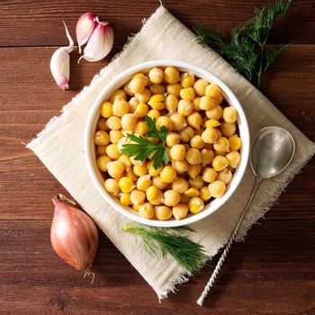 Cooked Chickpeas on bowl on a dark wooden table. Healthy, vegetarian nutritious protein food of Middle East. Top view.