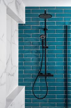 Dark aquamarine and white and color in the bathroom. Modern tiled shower with rain head, hand held shower