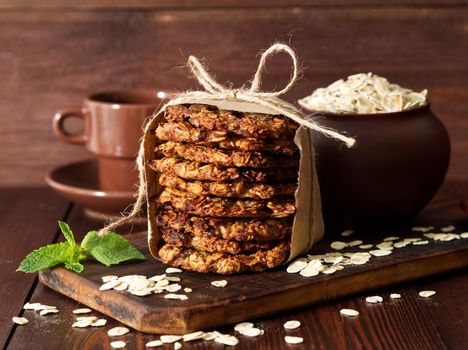 Homemade oatmeal cookies with banana, oats, nuts, eggs and flour free on a brown dark wooden table, side view.