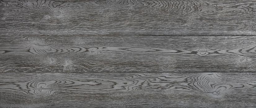 Black textured wooden background of horizontal planks with longitudinal fibers patterns and knots. Panoramic shot.