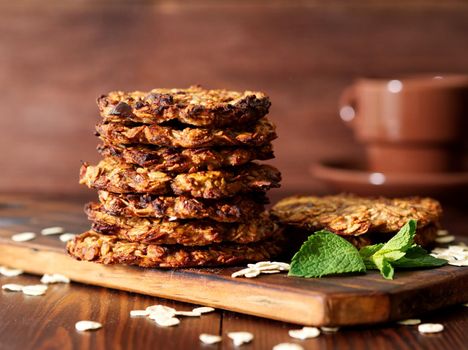 Homemade oatmeal cookies with banana, oats, nuts, eggs and flour free on a brown dark wooden table, side view.