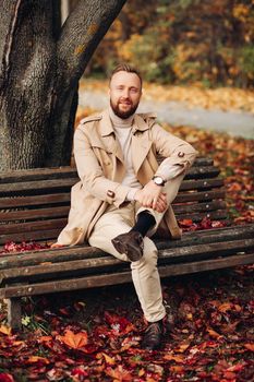 Portrait of a man in the forest with autumn leaves behind him.