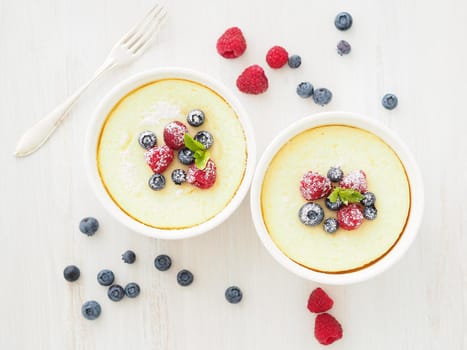 cheesecake decorated with raspberries, blueberries and mint in two ramekin, delicious dessert for a breakfast, top view