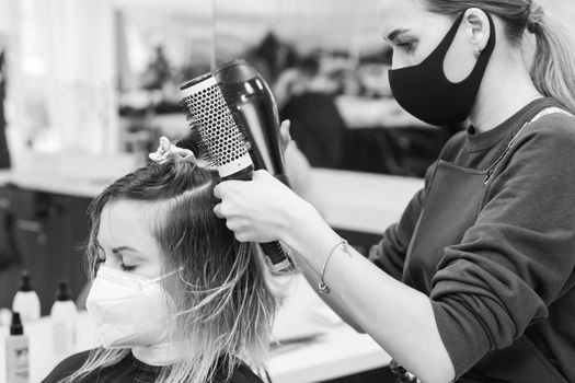 The stylist uses a hair dryer to style the hair after coloring. new