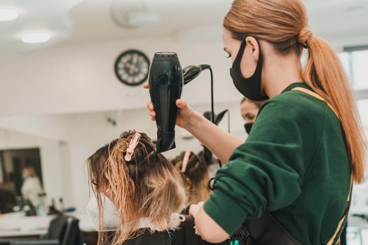 The stylist uses a hair dryer to style the hair after coloring. new