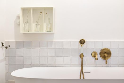 Retro style bathroom decorated in white with bathtub and vintage faucet and shower of bronze color.