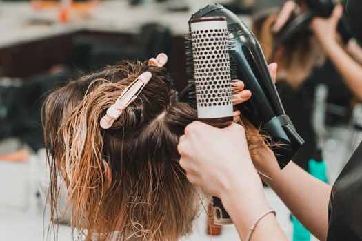 Hairdresser in a mask with at work, drying hair in a barbershop, client and stylist in masks. new