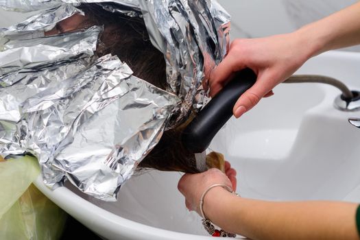 Washing hair dye from a hairdresser, removing foil from hair. new