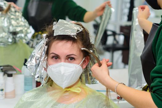 Woman dyes her hair in a barbershop, the process of dyeing her hair with foil. new