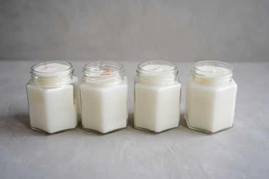 A set of candles made of natural soy wax in glass jars. Candles with wooden crackling wicks and cotton reinforced wicks. Scented container candles.