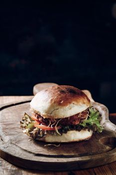 Hamburger on a black background on a wooden stand. High quality photo