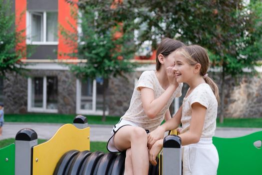 sisterhood, friendship. two charming teen girls having fun on a modern playground. sister, bffs communication.
