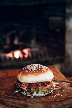 Juicy hamburger on a wooden stand on a black background. High quality photo