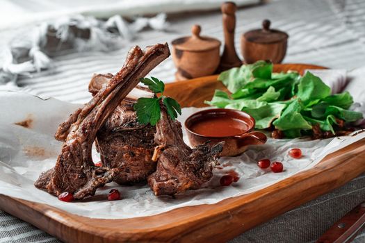 Grilled lamb loin on a wooden plate with lettuce leaves. High quality photo