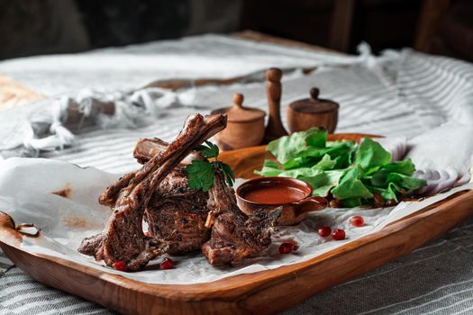 Grilled lamb loin on a wooden plate with lettuce leaves. High quality photo