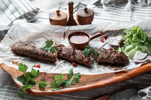 Kebab with sauce and greens on a plate. High quality photo