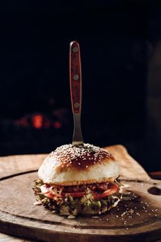 Juicy hamburger on a wooden stand on a black background. High quality photo