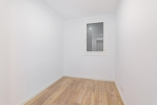 Empty room after renovation with white walls and dust window without natural light. Typical apartment in Barcelona.