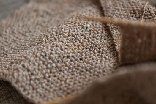 Handmade knitted scarf of sand color. Close-up of Wool texture. Selective focus