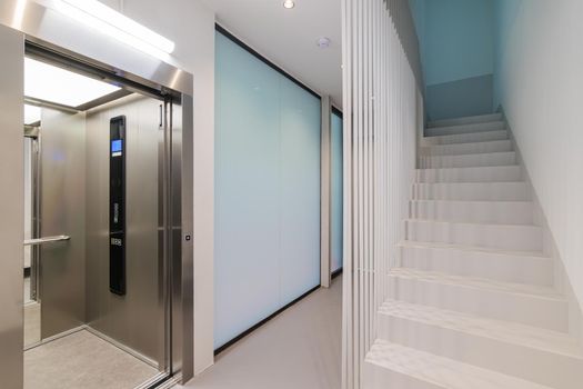 Corridor with passenger lift and stairs leading up. Interior of modern residential building