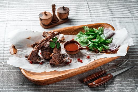 Grilled lamb loin on a wooden plate with lettuce leaves and wine. High quality photo