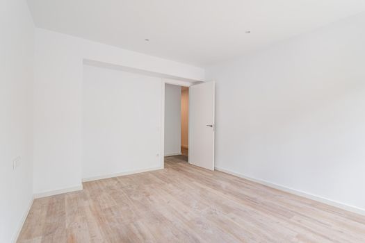 Empty white room after renovation with dusty wooden floor.