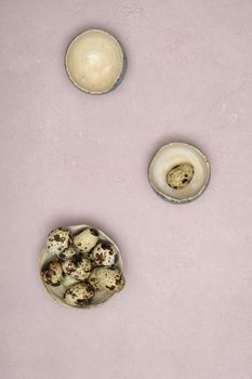 quail eggs in ceramic vases, gray feathers on the table, easter still life, natural food, diet and antioxidants, dark key and shallow depth of field. High quality photo