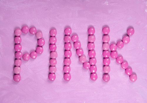 the word pink is written with pink sweets candies, on the pink background. High quality photo