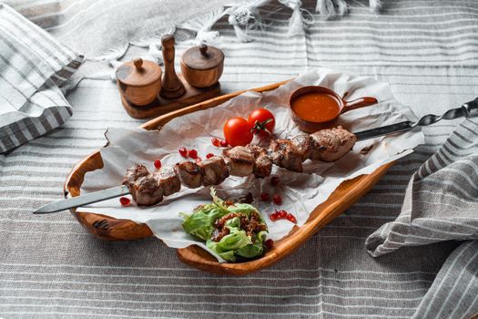 Barbecue with tomatoes and herbs on a wooden plate with paper. High quality photo