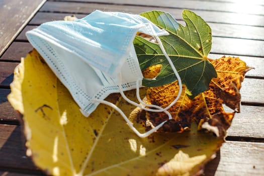 Medical mask rests on yellow autumn leaves . High quality photo