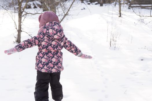 Winter, family, childhood concepts - authentic little preschool minor girl walking in snowy frosty cold weather day in park. happy little kid have fun run Straightened their arms like plane outdoors.