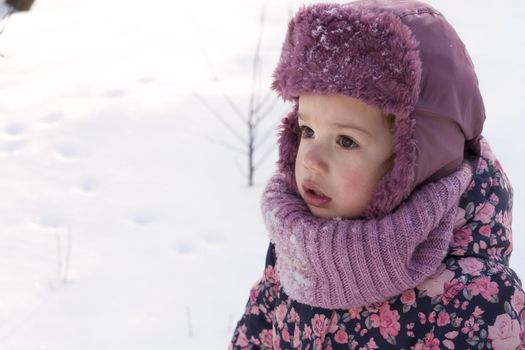 Winter, family, childhood concepts - close-up portrait authentic little preschool minor girl in pink look around in snowy frosty weather. surprised mysterious worried kid face outdoors. copy space.