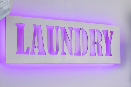 Glowing neon laundry sign on a white background. Illuminated signboard self-service laundry.