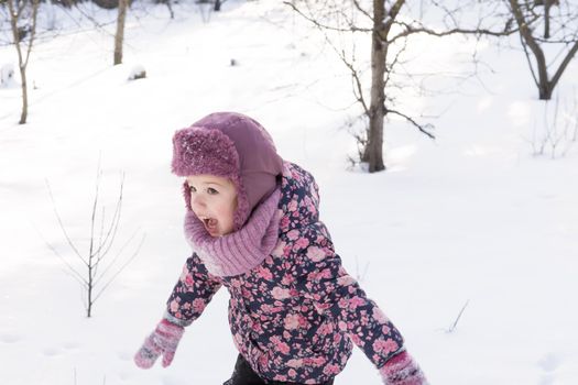 Winter, family, childhood concepts - authentic little preschool minor baby girl in pink warm clothes walking in snowy frosty cold weather day in park. happy pretty cute kid have fun joy run outdoors.
