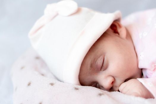 Childhood, care, motherhood, health concepts - Close up Little peace calm newborn baby girl in pink hat sleeps resting take deep nap laying on tummy on soft warm blanket pilow nest with close eyes.
