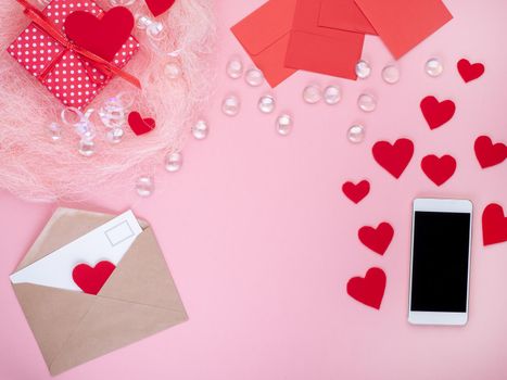 gift in red gift box with bow, smart phone, envelope, card, red heart, pink background, top view, copy space.