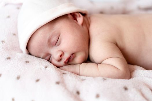 Childhood, care, motherhood, health, medicine, pediatrics concepts - Close up Little peace calm naked infant newborn baby girl in pink hat sleeps resting take deep nap laying on tummy on soft bed