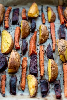 restaurant, vegetarianism, fast, healthy food, recipes concepts - Oven baked cut vegetables potatoes carrots, beets with seasoning dill. Roasted potatoes in jackets. Top view. Close up after cooking.