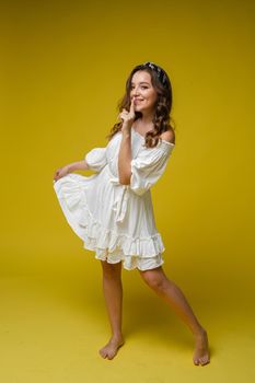 Cheerful excited asian woman use finger pointing to side with product or empty copy space standing over isolated yellow background. Model young girl laughing promotion.Advertisement presenting concept