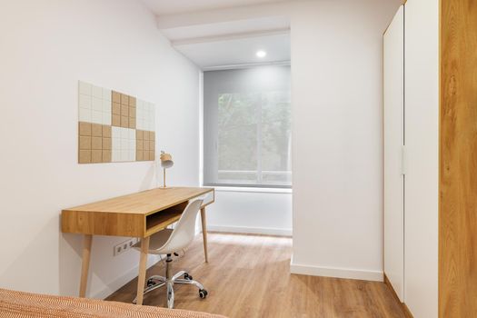 Stylish and minimalist room interior with modern comfortable workplace. Wooden table and floor with white wall and chair