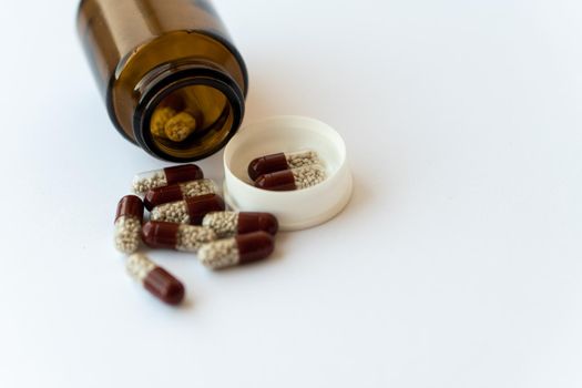 Medicine and pills. Medicines on a white background close-up. Brown glass bucket with capsules inside on a white background. Pills that spilled out of an inverted jar onto a white surface