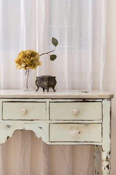 A bouquet of dried flowers and vintage jewelry box placed on retro style furniture