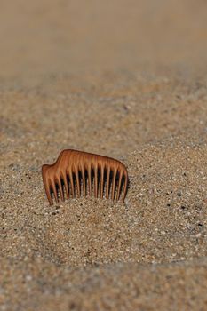 Natural wooden comb made of pear tree for scalp massage and aroma combing on the beach in sand at the sunset
